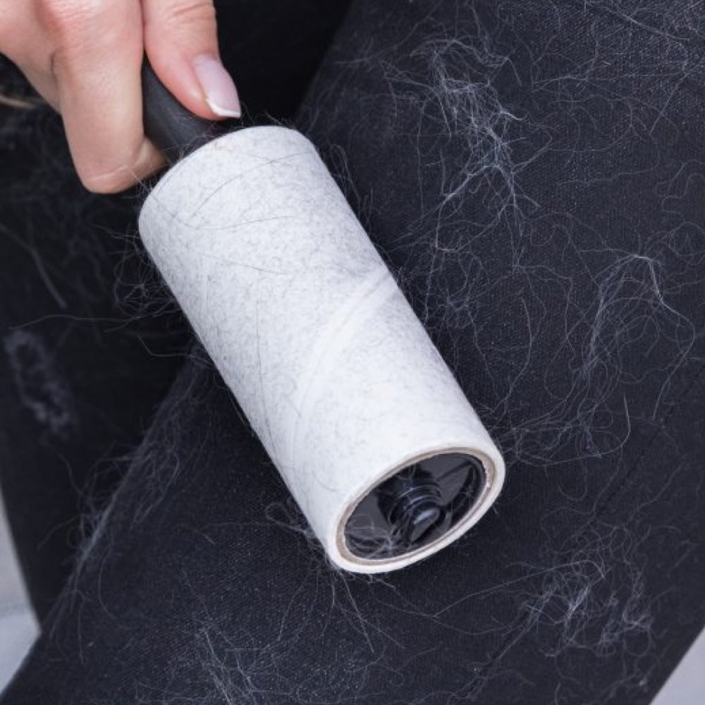 A lint roller clogged with pet hair after one pass over black jeans